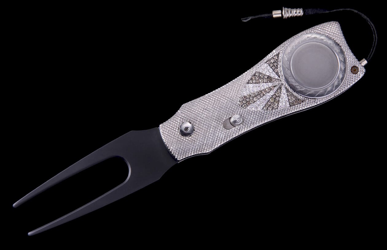 Luxury multi-tool knife with a silver-tone, diamond-encrusted handle featuring a sunburst pattern, black divot repair prongs, and a ball marker.