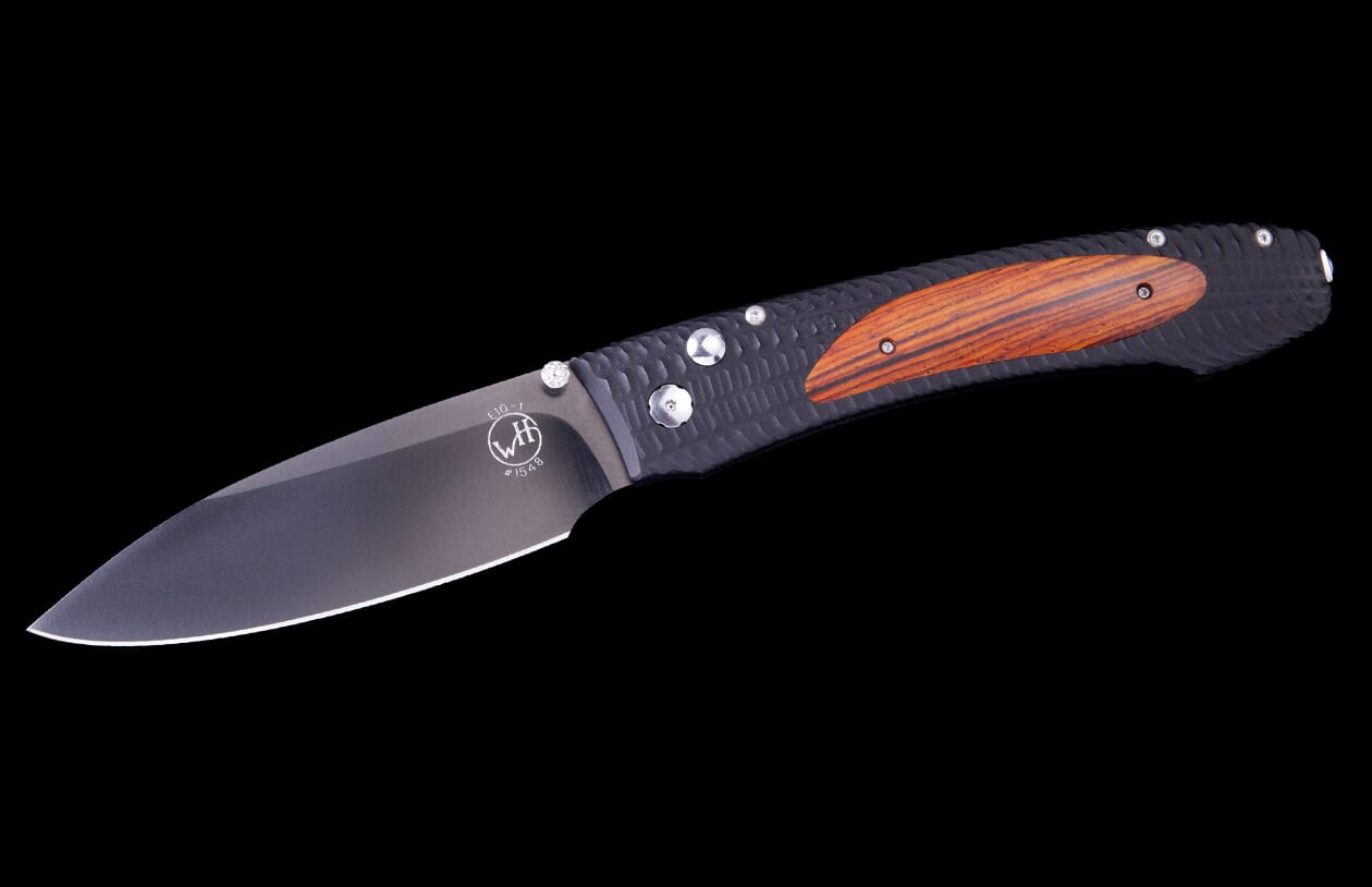 A dark gray folding knife with a textured black handle featuring an orange-brown wood inlay.