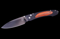 A dark gray folding knife with a textured black handle featuring an orange-brown wood inlay.