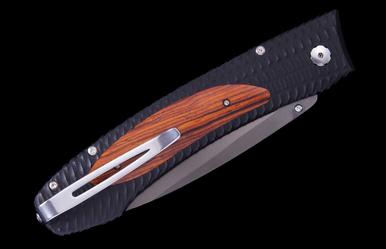 Closed folding knife with a textured black handle, orange wood inlay, a dark gray blade, and a silver pocket clip.