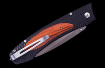 Closed folding knife with a textured black handle, orange wood inlay, a dark gray blade, and a silver pocket clip.