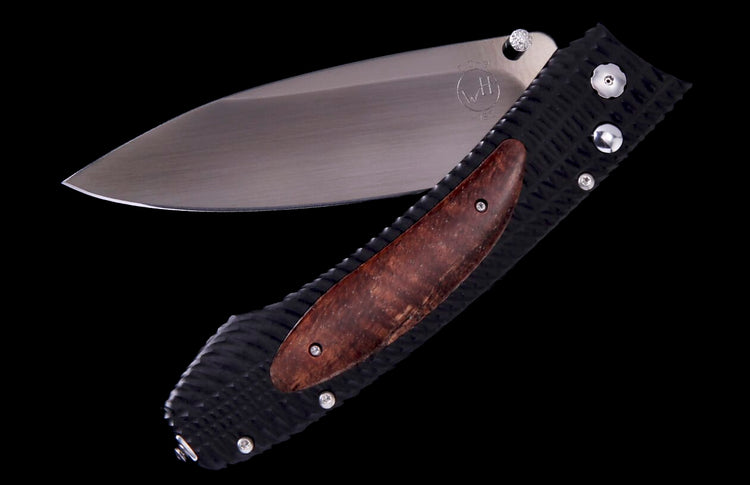 Partially open folding knife with a textured black handle, a brown wood inlay, and a silver blade with a thumb stud.