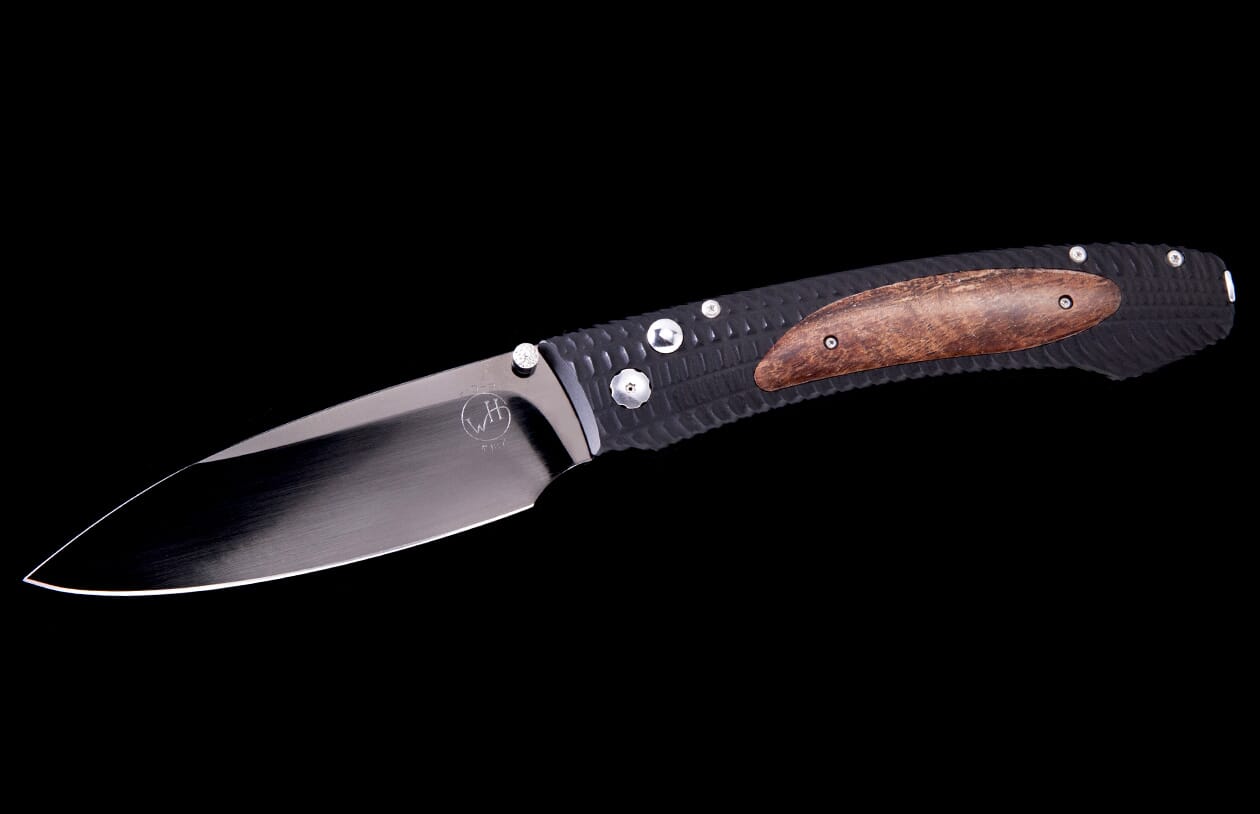 A folding knife with a shiny silver blade, black textured handle, and a brown wooden inlay, viewed from the side.