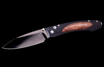 A folding knife with a shiny silver blade, black textured handle, and a brown wooden inlay, viewed from the side.