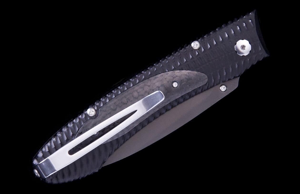 E6 3 folding knife of dark carbon fiber and metal, featuring a textured handle, silver pocket clip, and dark blade.