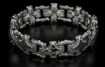 Ornate sterling silver bracelet with intricate links, textured dark brown panels, and a clasp featuring a clear and amber gemstone.