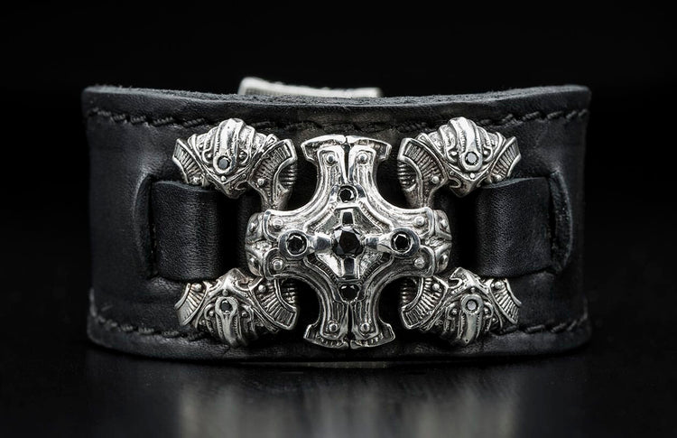 Black leather bracelet featuring an ornate silver centerpiece with black gemstones and intricate ram head side accents.