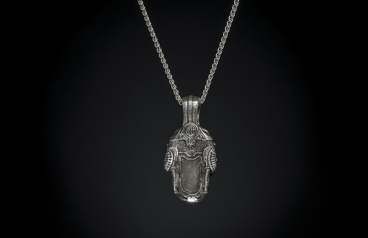 Silver pendant necklace featuring an intricate, sculpted design with "WH" initials, hanging on a silver chain.