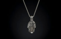 Silver pendant necklace featuring an intricate, sculpted design with "WH" initials, hanging on a silver chain.
