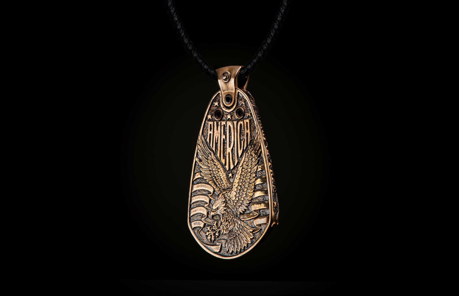 Aged bronze pendant featuring an embossed bald eagle, 'AMERICA' text, and flag details, worn on a black braided cord.