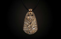 Aged bronze pendant necklace featuring a bald eagle, "AMERICA" text, stars, and stripes, suspended from a black cord.