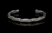 Silver bracelet with gold accents on a black background
