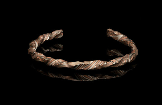 Metallic bracelet with a twisted design on a black background