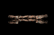 Metallic bracelet with a twisted design on a black background