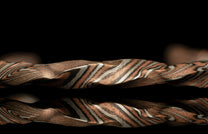 Metallic bracelet with a twisted design on a black background