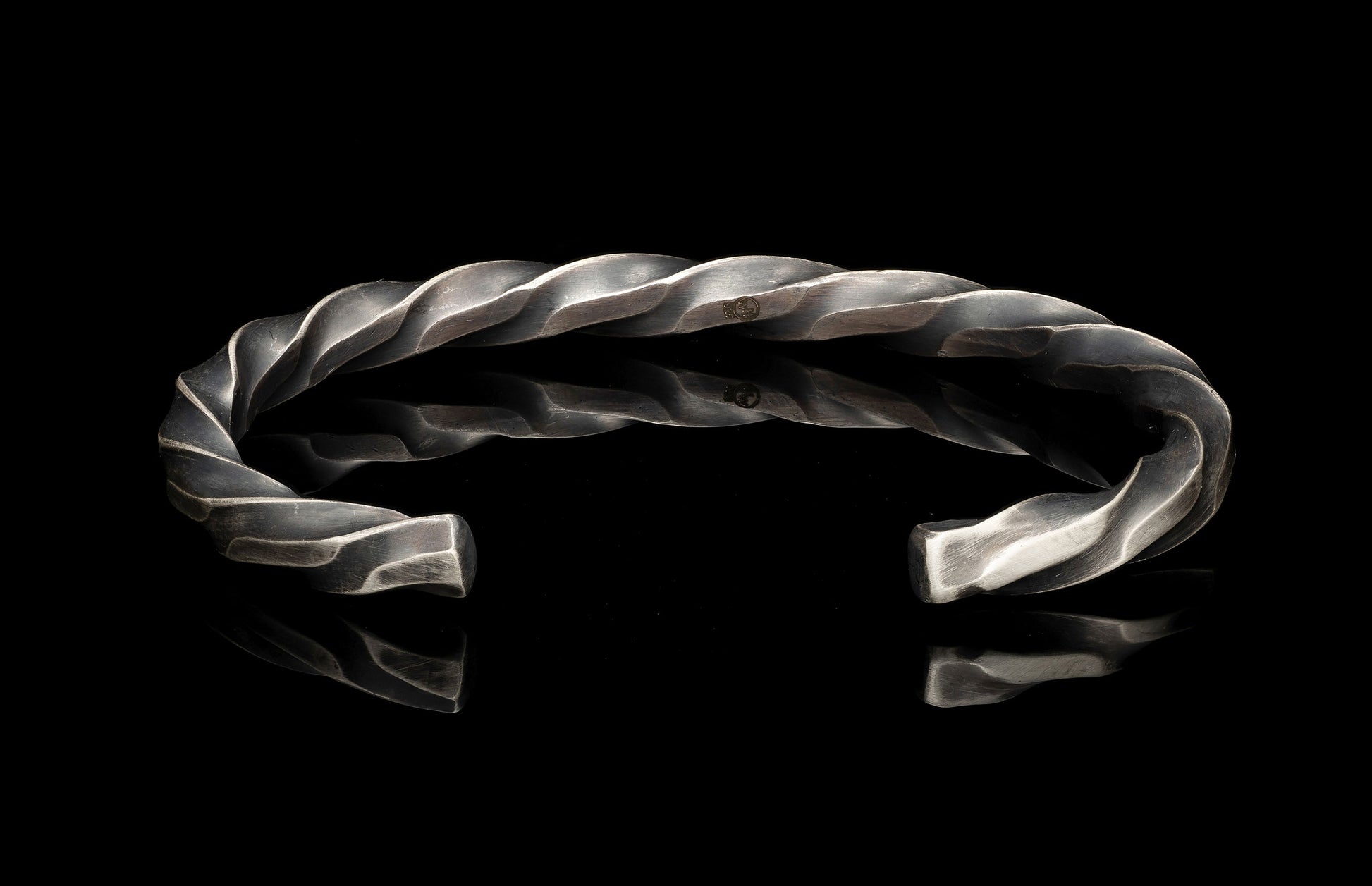 Silver bracelet with a twisted design on a black background