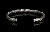 Silver bracelet with a twisted design on a black background