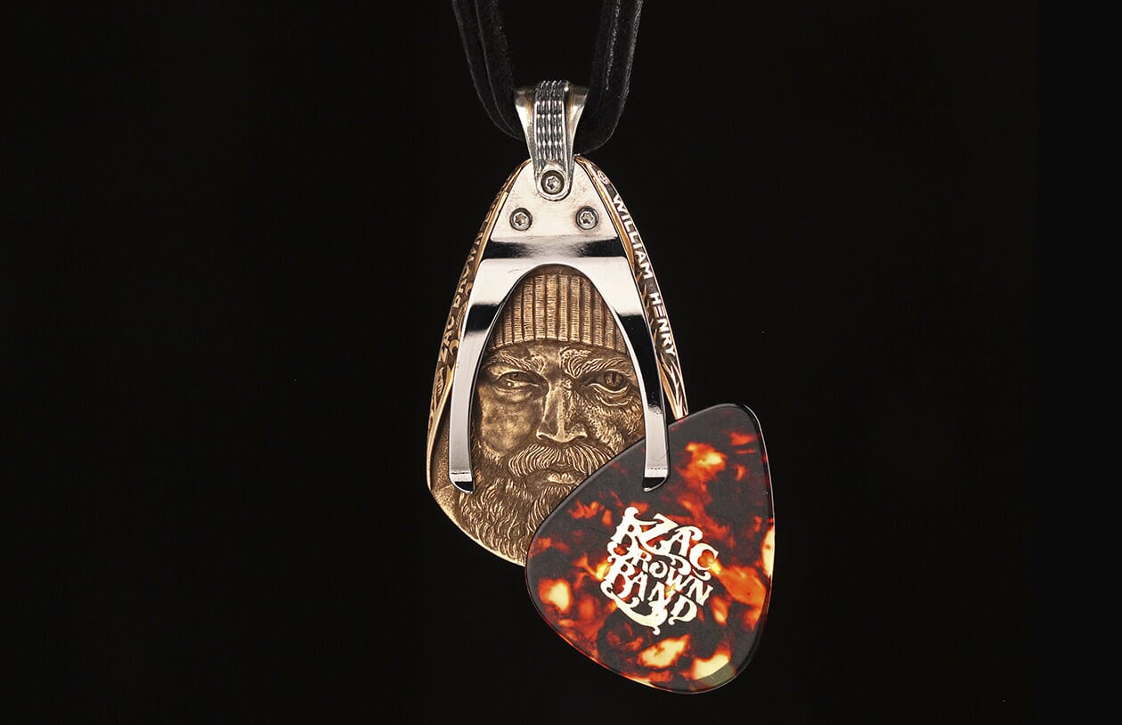 Bronze pendant featuring a bearded man's face, set in a silver-tone frame with a tortoiseshell Zac Brown Band guitar pick.