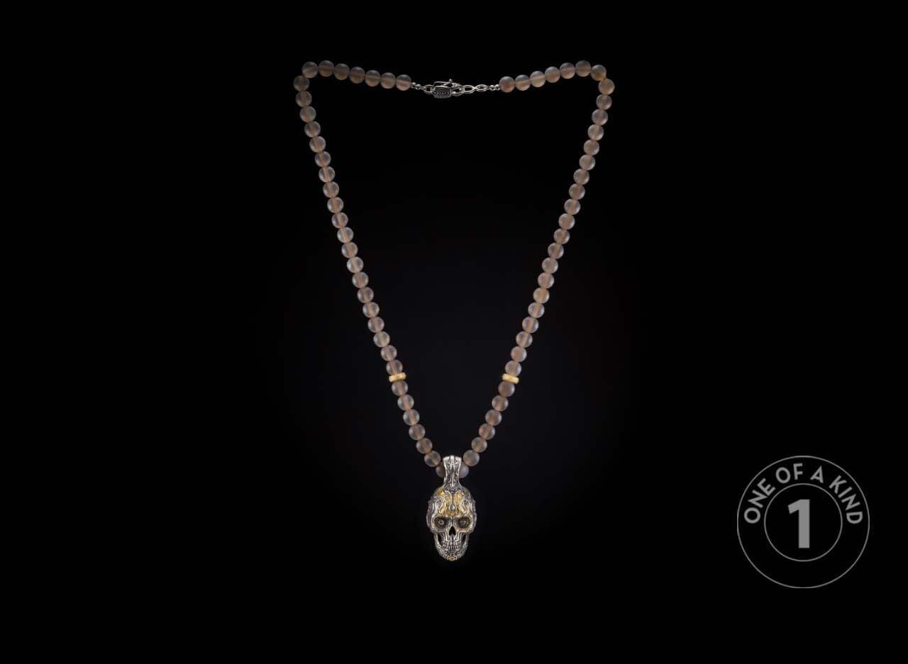 One of a kind necklace from William Henry featuring a sterling silver skull pendant with cognac gems & 23.5K gold foil on a necklace of chalcedony beads with 18K gold rondelles.