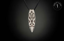 Silver pendant with dark etched patterns, a red gemstone, and black braided cord.