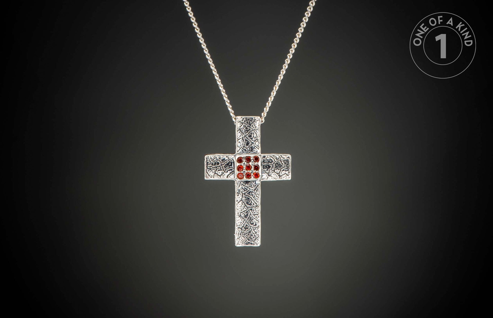 Silver cross pendant necklace with ornate texture, nine central red gemstones, and a "One of a Kind 1" logo.