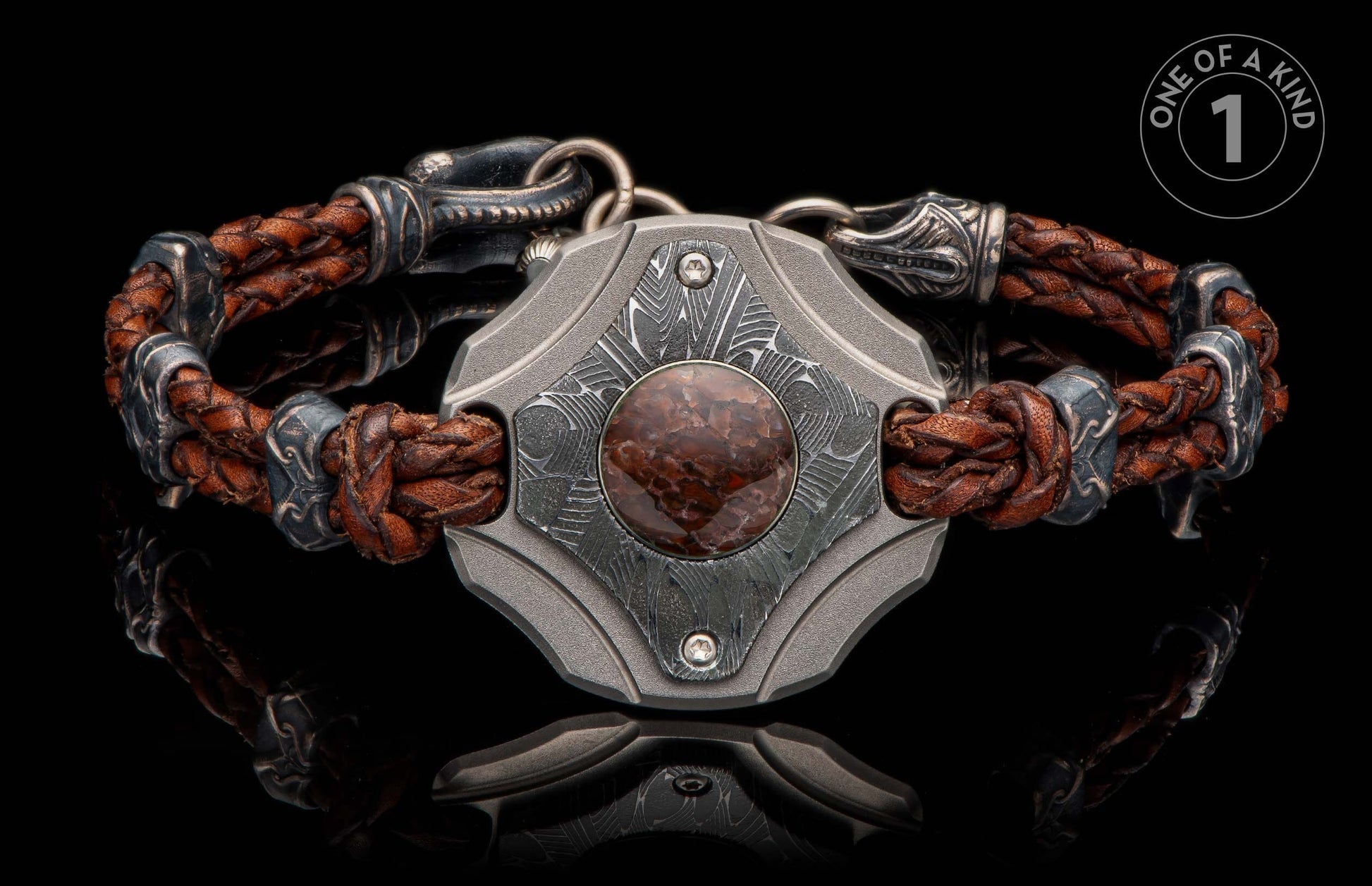Brown braided leather and dark metal bracelet with a central shield, reddish-brown stone, and intricate Damascus pattern.