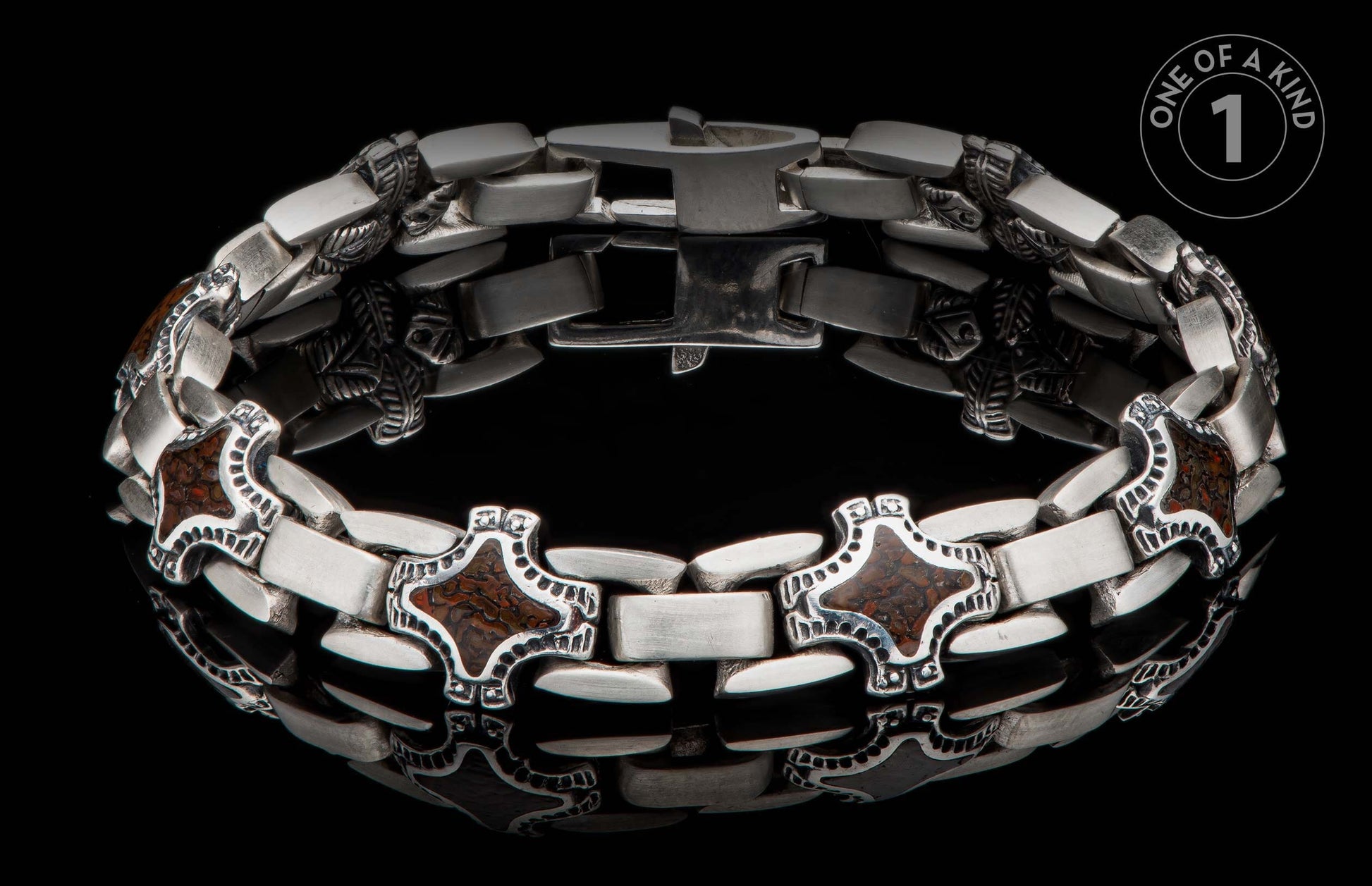 A chunky silver-toned metal bracelet with decorative cross-shaped links featuring brown patterned inlay, on a reflective black surface.