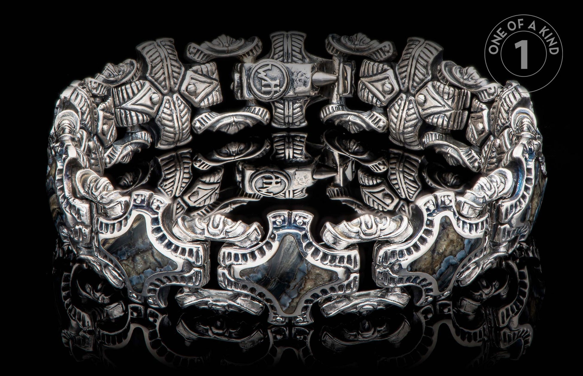 Intricately designed silver bracelet with hammer motifs and natural stone inlays.