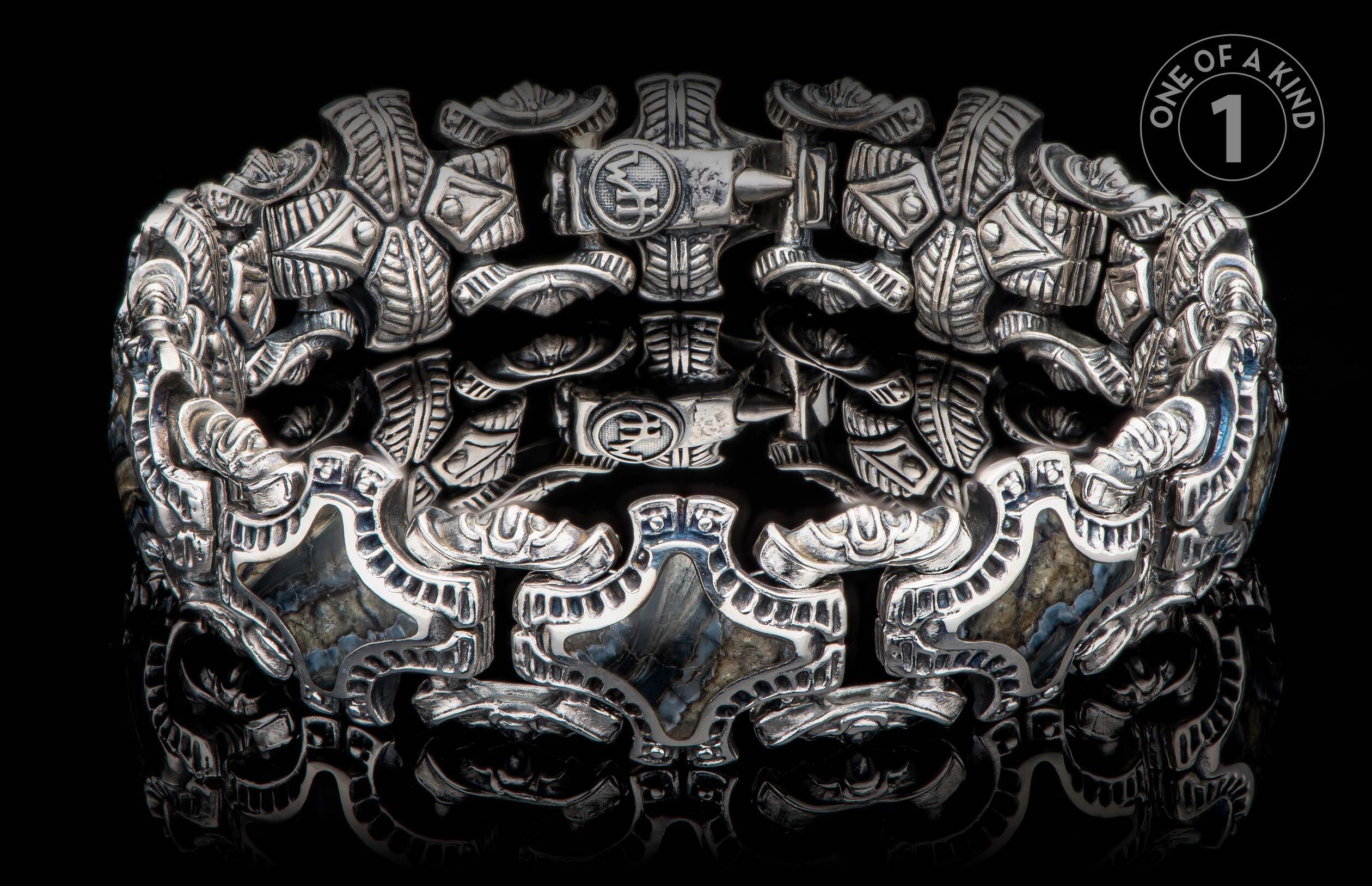 Intricately designed silver bracelet with hammer motifs and natural stone inlays.