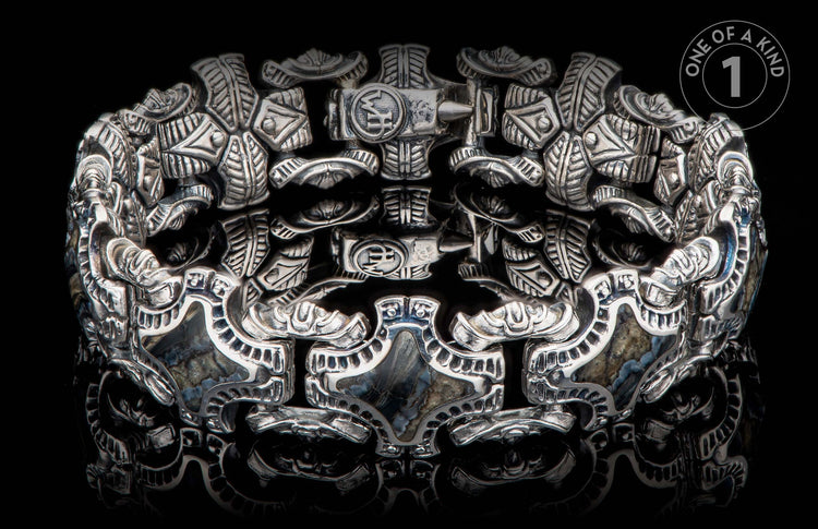 Intricately designed silver bracelet with hammer motifs and natural stone inlays.