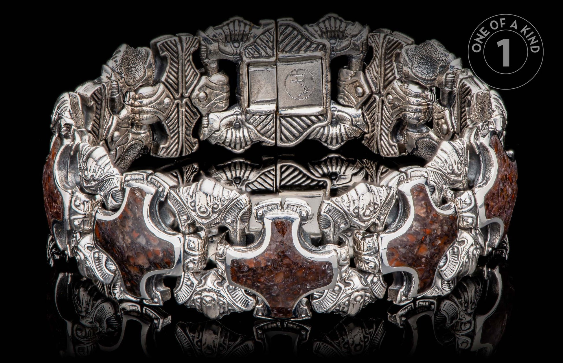 Ornate silver-toned bracelet with dark reddish-brown stone inlays, featuring intricate carved figures and a prominent clasp with "WH" initials.