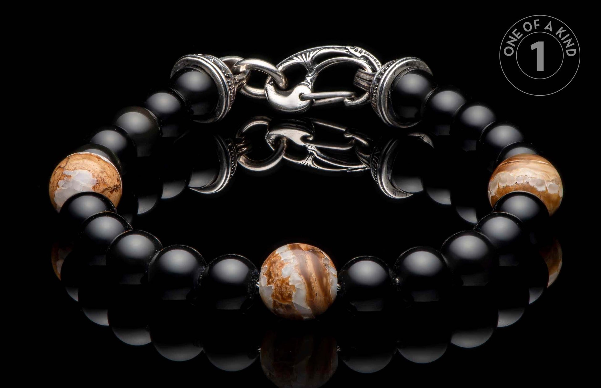 Black beaded bracelet with three patterned brown and white stone beads and an ornate silver hook clasp.