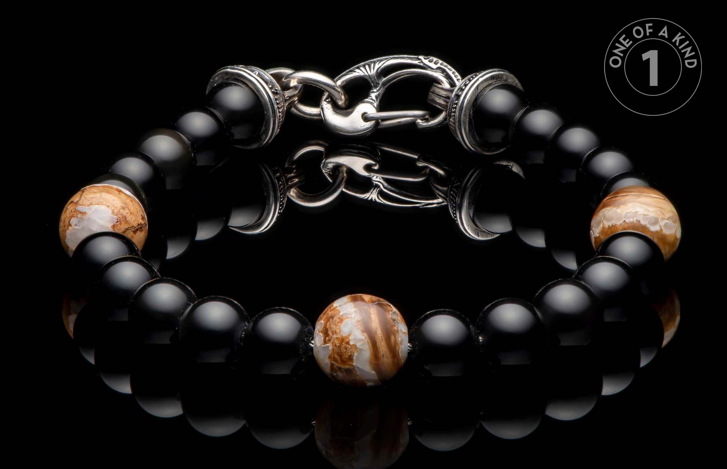 Black beaded bracelet with three patterned brown and white stone beads and an ornate silver hook clasp.