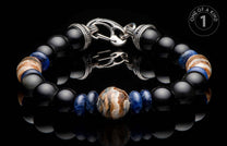 Beaded bracelet with black onyx, blue sodalite, and central fossil mammoth tusk, silver-toned clasp, displayed on a reflective surface with a 'ONE OF A KIND' logo.