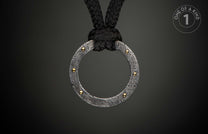 Damascus steel ring pendant with swirling patterns and gold rivets, suspended from a black braided rope.