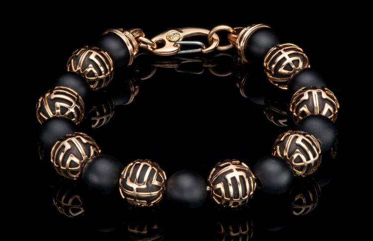 Black matte beaded bracelet with patterned rose gold metal beads and a rose gold lobster clasp on a reflective surface.