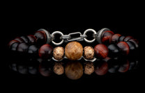 Beaded bracelet with dark red, black, and light brown textured beads, featuring ornate silver-tone metal rings and clasp, laid flat with reflection.