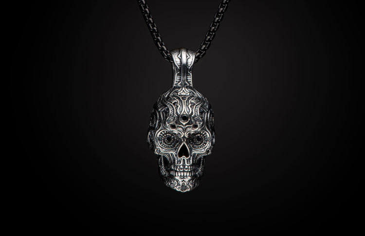 Front-facing silver skull pendant with intricate filigree patterns and black stone accents on a dark chain.