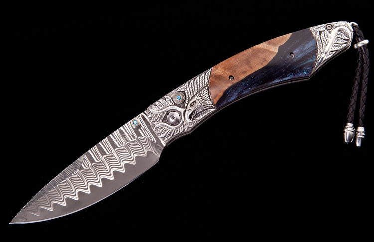 Ornate folding knife with a wavy Damascus steel blade, engraved silver hilt featuring a bird head and turquoise accents, wood and resin handle, and braided leather lanyard.