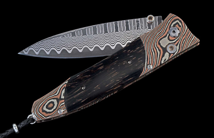 A folding knife with a dark handle, a wavy Damascus steel blade, and a copper and grey patterned frame.