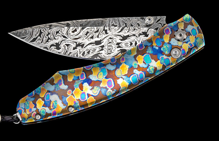 One of a kind William Henry custom knife with hand forged Damascus steel, Laser-colored titanium, and white topaz gemstones.