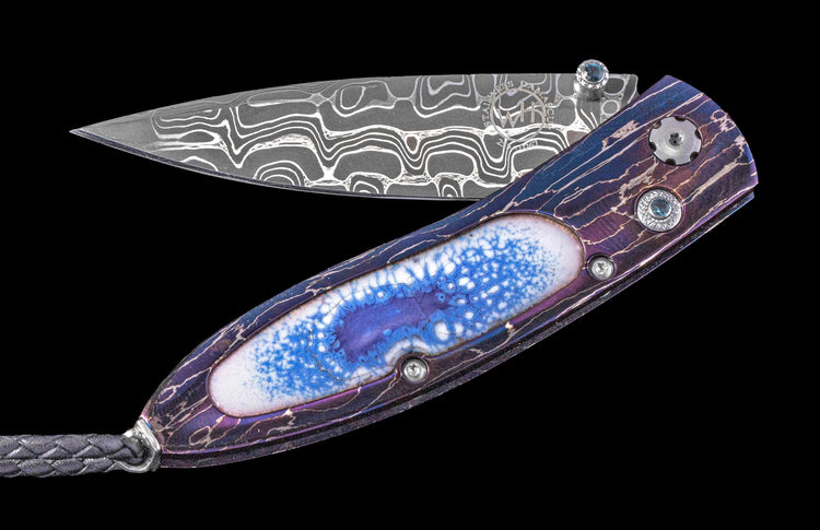 One of a William Henry Custom Knife with Heat-blued damascus frame, enamel scales, Blue topaz gems, and damascus steel blade