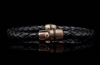 Black braided leather bracelet with a striped metallic clasp in bronze and silver tones, featuring an orange gemstone.