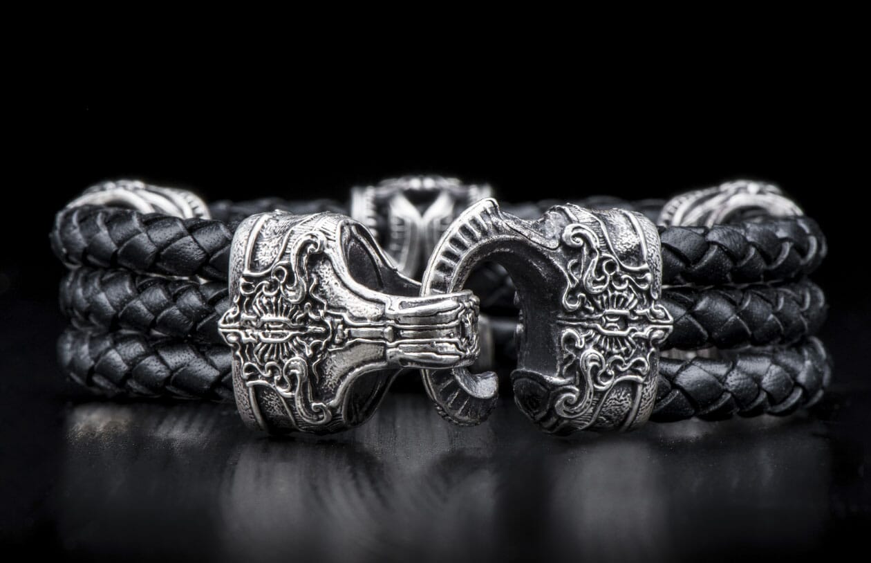 Black braided leather bracelet with ornate silver-tone clasps featuring intricate scrollwork.