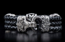 Black braided leather bracelet with ornate silver-tone clasps featuring intricate scrollwork.