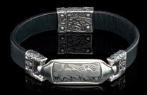 Black leather bracelet with an ornate silver centerpiece and Damascus steel inlay.