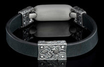 Black leather bracelet with a brushed silver metal plaque and ornate silver skull-motif clasp.