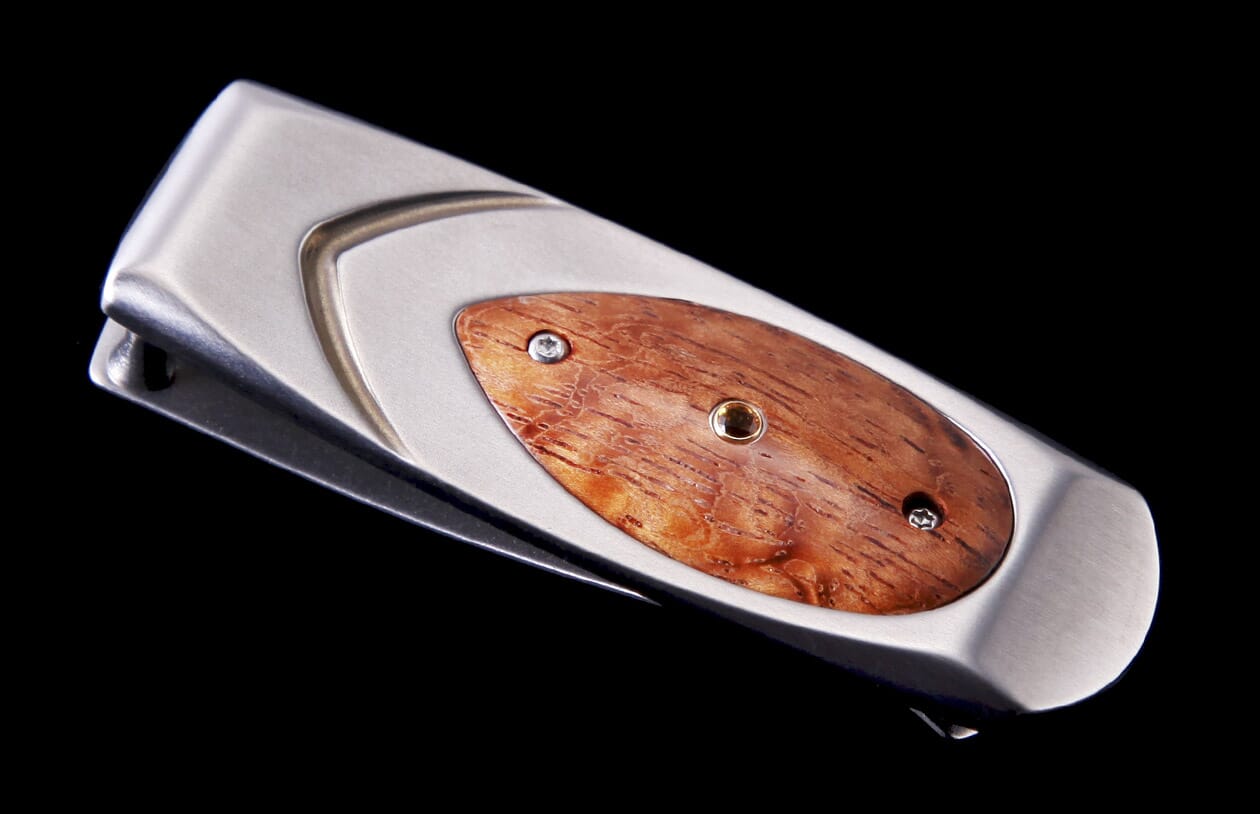 Silver-toned money clip by Geneva, featuring an oval reddish-brown wood inlay with textured grain and small metallic fasteners.
