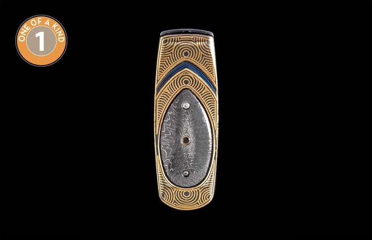 Gold and blue money clip with concentric patterns, a central blue stripe, and a dark oval insert with two decorative dots.