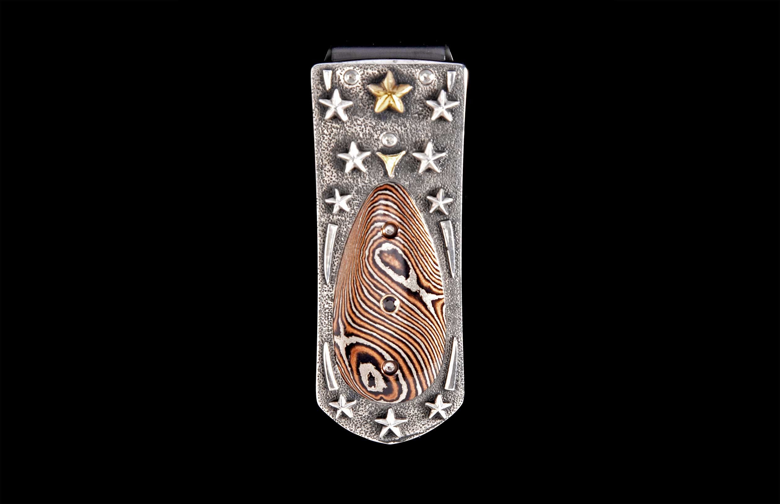 Silver-toned hammered money clip featuring a central teardrop inlay with wavy brown and white patterns, accented by silver and gold stars.